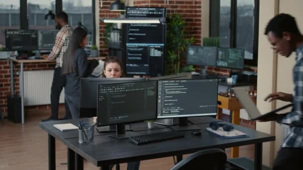 Senior developer coding on laptop at desk with computer screens parsing code — стоковое видео