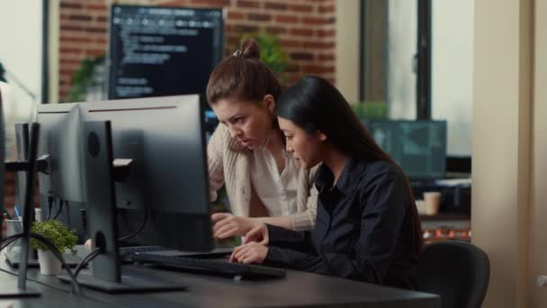 Equipo de compañeros de trabajo que compara los códigos fuente que se ejecutan en la pantalla del ordenador portátil y monitor — Vídeo de stock