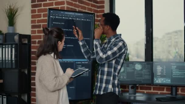 Software developers analyzing source code on wall screen tv comparing errors using digital tablet — Stok video