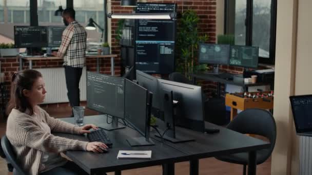 Software engineer typing source code on computer keyboard while colleagues sit down at desk — Wideo stockowe