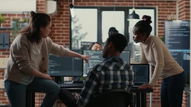 Systemingenjör sitter på skrivbordet och diskuterar med ett blandat team av kodare om ai innovation — Stockvideo
