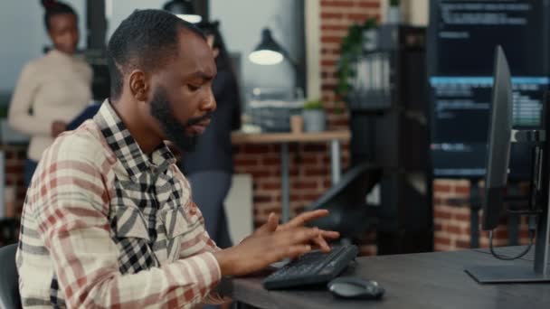 Триножний знімок афроамериканського хмарного програміста, що пише код, зосереджений на екрані комп'ютера — стокове відео