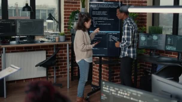 Team of database admins analyzing source code on wall screen tv comparing errors using digital tablet — Vídeo de stock