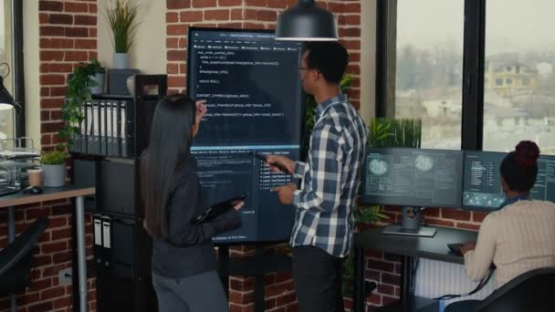 Ingénieurs logiciels analysant le code sur écran mural TV comparer les erreurs à l'aide d'une tablette numérique — Video