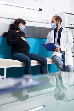 Woman expecting child meeting with health specialist in office