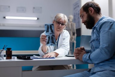 Doctor explaining radiography diagnosis to man with disease in cabinet