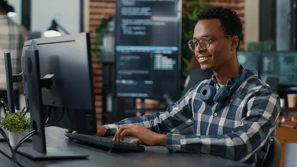 Portrait of software engineer writing code arranging glasses and being happy about parsing results — стоковое фото