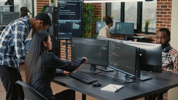 Mixed team of programmers analyzing source code pointing at screens comparing algorithm — Photo
