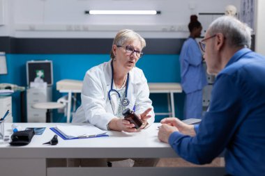 Woman doctor giving bottle of pills to senior patient with disease