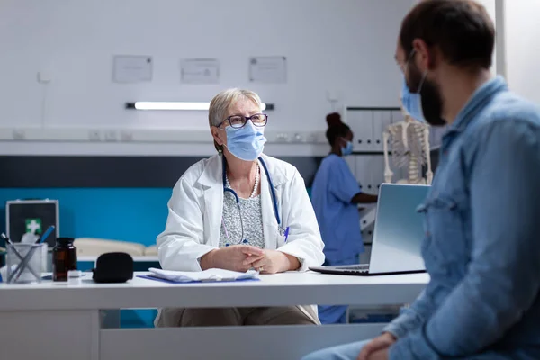 General practitioner talking to man about disease and healthcare, wearing face mask — Stock Photo, Image