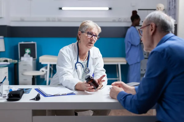 Woman doctor giving bottle of pills to senior patient with disease — Stock Photo, Image