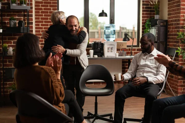 Psychologist giving hug to man after sharing recovery progress with people at aa meeting — Stockfoto