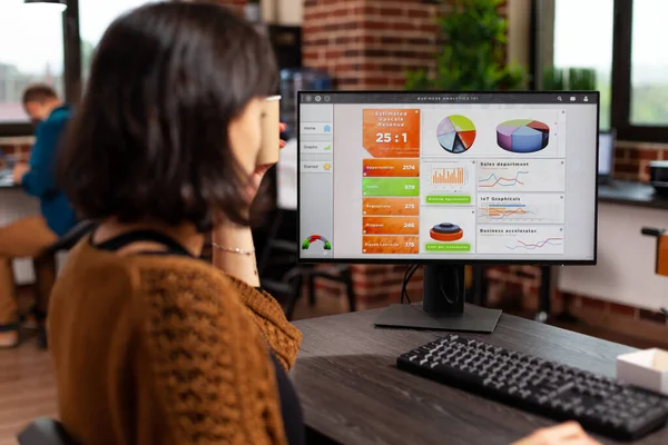 Entrepreneur woman holding cup of coffee analyzing company graphs typing management strategy — Stockfoto