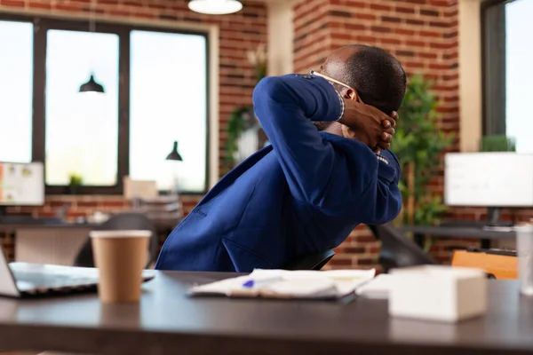 Entrepreneur sitting with hands over head to relax after finishing task in office — стоковое фото