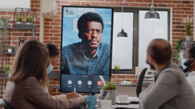 Çeşitli iş arkadaşları çevrimiçi video konferansında adamla konuşuyor.