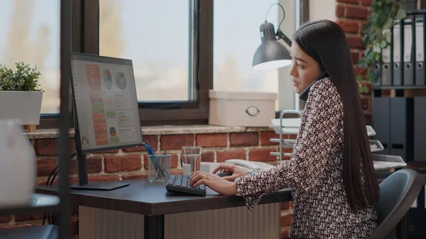 Aziatisch vrouw praten op telefoongesprek terwijl ze werkt — Stockfoto