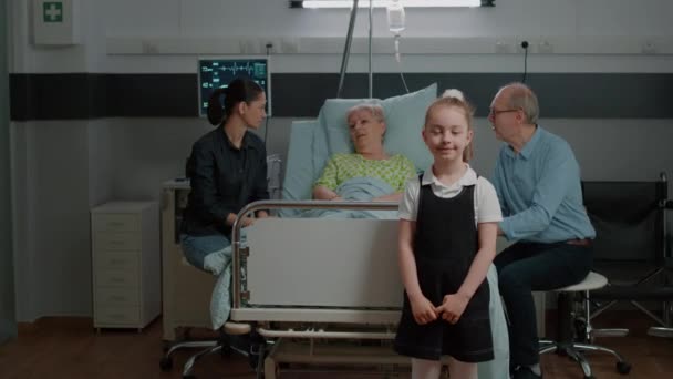 Retrato del niño en la sala del hospital visitando al paciente anciano en la cama — Vídeo de stock