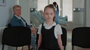 Tesisin bekleme salonunda sandalyede oturan çocuk portresi