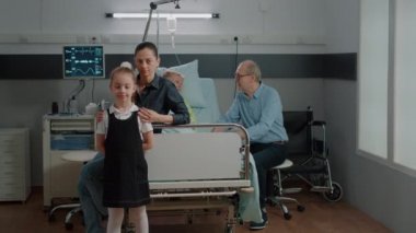 Emekli hasta koğuşunda aile ziyareti yapan kadın ve çocuğun portresi.