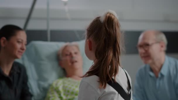 Close up of little girl talking to sick patient in bed at family visit — 图库视频影像