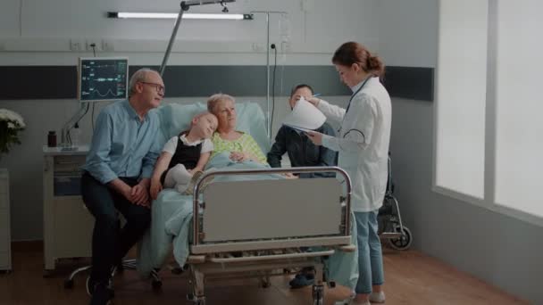 Abuela enferma y familia hablando con el médico sobre la atención médica — Vídeo de stock