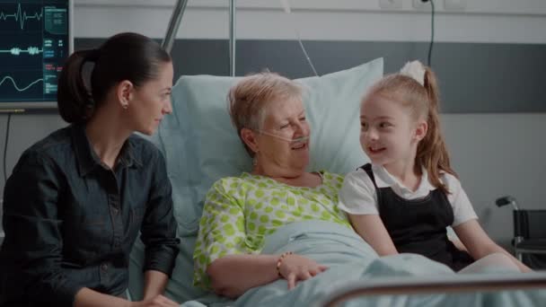 Én nyugdíjas élvezi látogatást unokahúga és lánya kórházi kórteremben ágyban — Stock videók