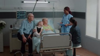 Nurse doing consultation with sick woman while family visits her