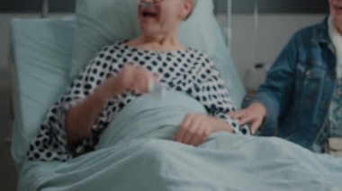 Hastane koğuşunda, yeğenleri ve kızı tarafından ziyaret edilen emekli adama yakın durun.