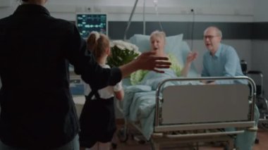 Hastane koğuşundaki çocuk ve anne yaşlı hastayı ziyaret ediyor.