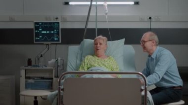 Niece and daughter visiting sick grandma in hospital ward bed