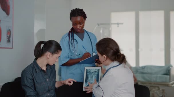 Close up of multi ethnic team explaining x ray diagnosis on tablet — Stockvideo