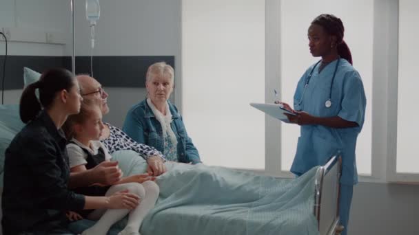 African american assistant explaining medication to old man and visitors — 图库视频影像