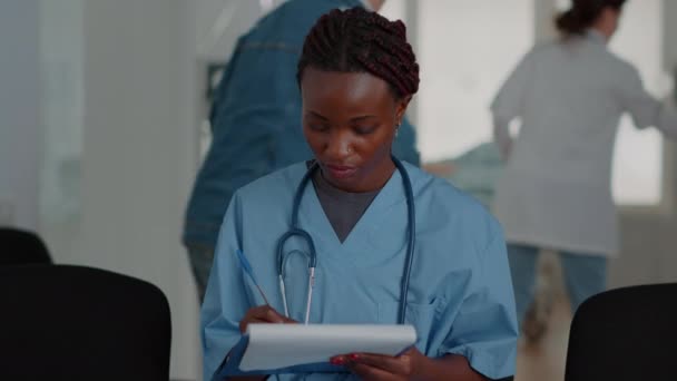 Primer plano de la enfermera afroamericana mirando los archivos de chequeo en la sala de espera — Vídeos de Stock