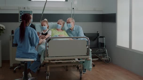 Asystent medyczny wyjaśniający diagnozę pacjentowi i rodzinie na oddziale szpitalnym — Wideo stockowe