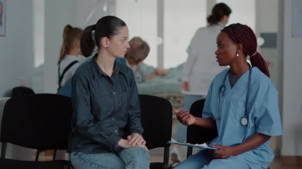 Nő beszél orvosi asszisztenssel a váróban — Stock videók