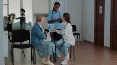 Hastalığı olan yaşlı hastaya X ışını teşhisini açıklayan çok ırklı tıbbi ekip