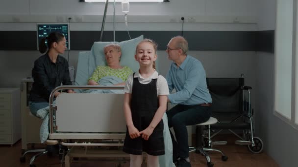 Portrait of child visiting senior woman in hospital ward with mother — Stockvideo