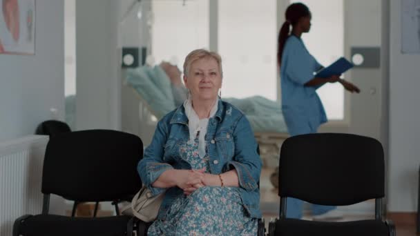 Portrait of aged woman sitting on chair in waiting room — 비디오