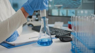 Bilim adamı, maddeyi mikro pipet ve beher ile karıştırıyor.