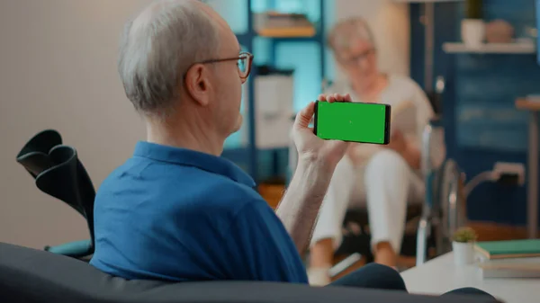 Uomo anziano utilizzando lo schermo verde orizzontale sul telefono cellulare — Foto Stock