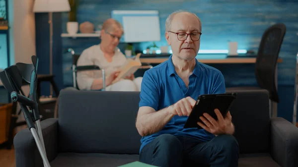 拿着数码平板电脑与退休人士进行视频通话 — 图库照片