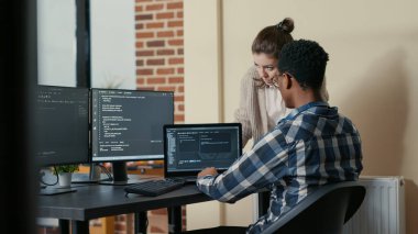 Two programmers doing high five hand gesture at desk with multiple screens running code celebrating