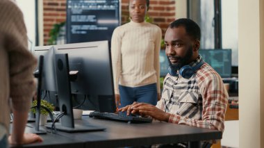Relaxed software developer wearing wireless headphones smiling working looking at computer screen