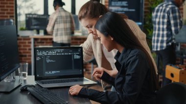 Team of software developers talking about source code running on laptop screen
