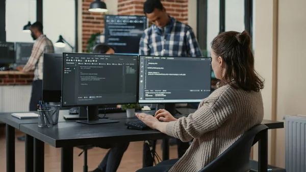 Desarrollador de software enfocado escribiendo código mirando múltiples pantallas de computadora —  Fotos de Stock