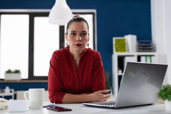 Portrait of businesswoman with laptop sitting at desk in startup office. — стоковое фото