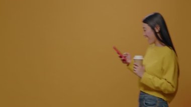 Elinde akıllı telefon ve bir fincan kahve tutan mutlu insan.