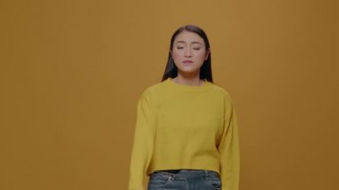 Asian woman doing silent gesture with index finger over lips