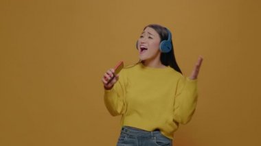 Happy woman with headphones singing at smartphone