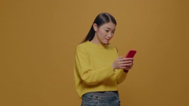 Asyalı kadın cep telefonundan iyi haberler aldığı için mutlu.